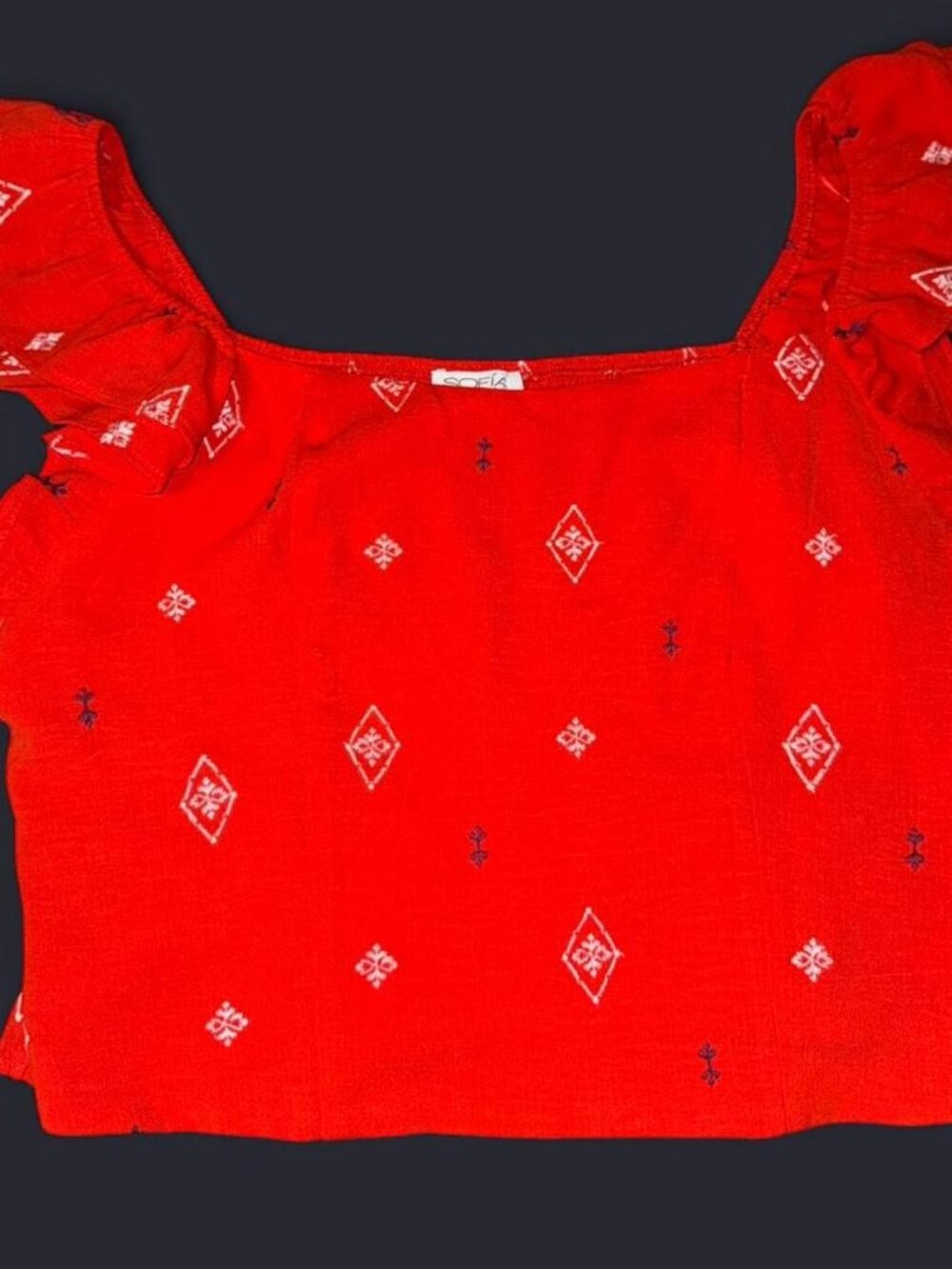Redish orange Sofia Vergara crop top with ruffles and white diamond pattern.